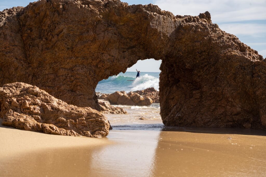 Stunning view of ALAIA surfer on wave through arch rock formation near La Fortuna, Baja California Sur, Mexico